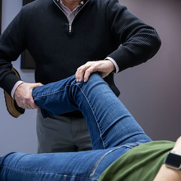 Patient is lying on their back while having their knee checked by a specialist