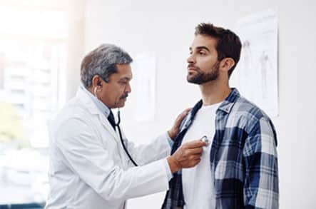 Doctor listening to a man's heart using a stethoscope.